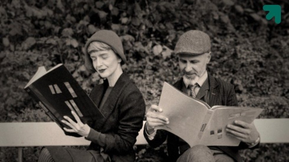 dwie osoby stylizowane na lata dwudzieste czytające gazetę