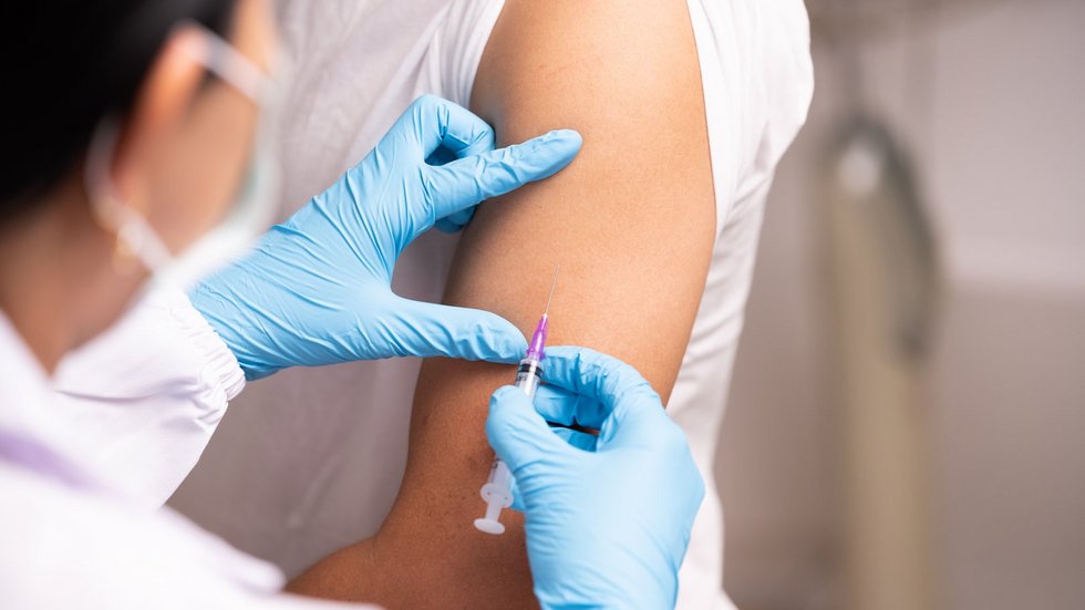 Doctor hand in blue gloves holding influenza vaccine for prevention human.Nurse holding syringe make injection in shoulder of patient in hospital.Covid-19 or coronavirus vaccine. Szczepienie